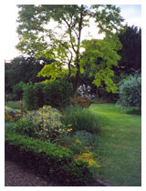 View across the lawn and through the flower beds in a country garden in Hertfordshire.