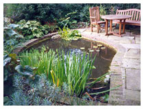 Pond, bog garden and york stone and brick patio in a corner of a country garden.