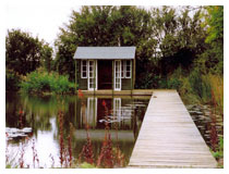 Large pond in a country garden, with walkway and lakeside chalet.