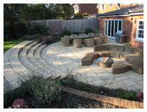 Sheltered patio for outdoor dining, barbecues, and entertaining.  Comfortable steps lead to the lawn.  Family garden design in Harpenden, Hertfordshire.