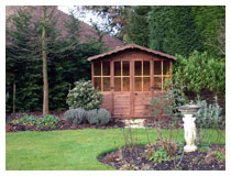 The chalet with evergreen shrubs that frame and partially conceal it.  The garden in winter.